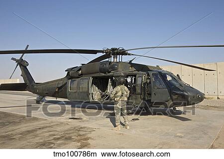 A U. S. Army crew chief stands next to a UH-60 Black Hawk. View Large Photo Image Picture - A U. S. Army crew chief stands next to a UH-60 Black Hawk.. Fotosearch