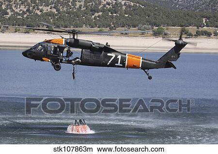 A U. S. Army UH-60 Black Hawk helicopter collects water from a reservoir. View Large Photo Image Picture - A U. S. Army UH-60 Black Hawk helicopter collects water from a reservoir.. Fotosearch
