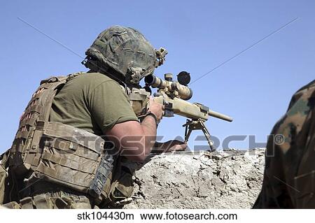 Picture - A U. S. Marine looks through the scope of an M40A1 sniper rifle.. Fotosearch