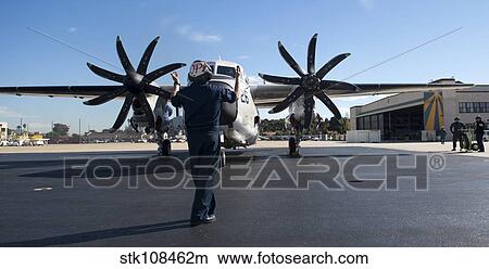 A U. S. Sailor signals to a C-2A Greyhound aircraft. View Large Photo Image Picture - A U. S. Sailor signals to a C-2A Greyhound aircraft.. Fotosearch