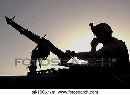 Picture - A U. S. soldier talks on a hand mike while providing security.. Fotosearch