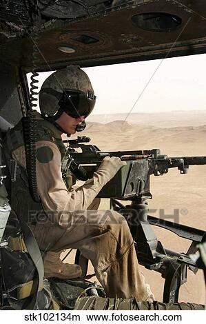 A UH-1N Huey crew chief scans the ground while manning a. 50 caliber machine gun. View Large Photo Image Picture - A UH-1N Huey crew chief scans the ground while manning a. 50 caliber machine gun.. Fotosearch
