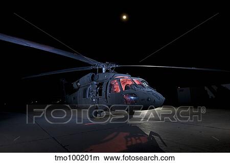 A UH-60 Black Hawk helicopter parked on the flight line under a full moon. View Large Photo Image Picture - A UH-60 Black Hawk helicopter parked on the flight line under a full moon.. Fotosearch