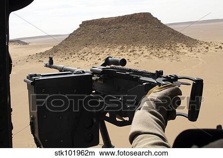 A UH-60 Blackhawk crew chief holds an M240G medium machine gun. View Large Photo Image Picture - A UH-60 Blackhawk crew chief holds an M240G medium machine gun.. Fotosearch