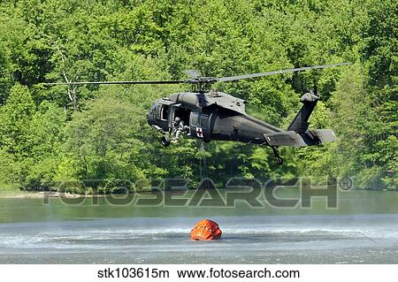 A UH-60 Blackhawk helicopter fills a suspended water bucket in Marquette Lake, Pennsylvania. View Large Photo Image Picture - A UH-60 Blackhawk helicopter fills a suspended water bucket in Marquette Lake, Pennsylvania.. Fotosearch