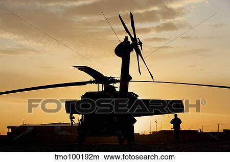 A UH-60L Black Hawk helicopter silhouetted by the setting sun. View Large Photo Image Picture - A UH-60L Black Hawk helicopter silhouetted by the setting sun.. Fotosearch