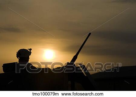 Picture - A US Soldier mans his. 50 caliber while waiting to move out on a mission at sunset.. Fotosearch