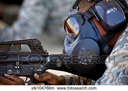 Picture - Air Force Basic Military Training trainee fires at his target while wearing his gas mask.. Fotosearch