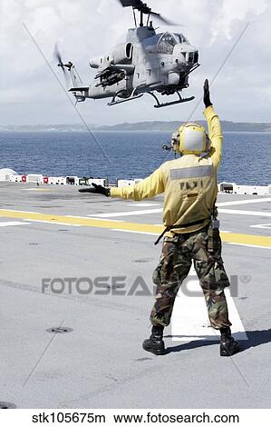 Airman directs an AH-1W Super Cobra onto the flight deck of USS Essex. View Large Photo Image Picture - Airman directs an AH-1W Super Cobra onto the flight deck of USS Essex.. Fotosearch