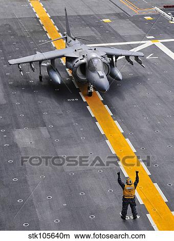 Airman directs an AV-8B Harrier II aircraft on the flight deck of USS Peleliu. View Large Photo Image Picture - Airman directs an AV-8B Harrier II aircraft on the flight deck of USS Peleliu.. Fotosearch