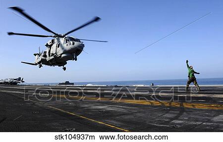 Airman directs an EH-101 Merlin helicopter onto the flight deck of USS John C. Stennis. View Large Photo Image Picture - Airman directs an EH-101 Merlin helicopter onto the flight deck of USS John C. Stennis.. Fotosearch