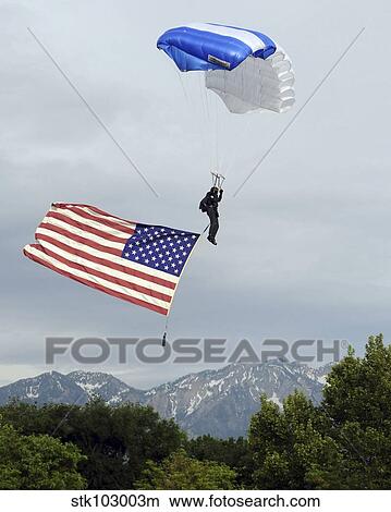 Airman floats through the sky carrying the American flag. View Large Photo Image Picture - Airman floats through the sky carrying the American flag.. Fotosearch