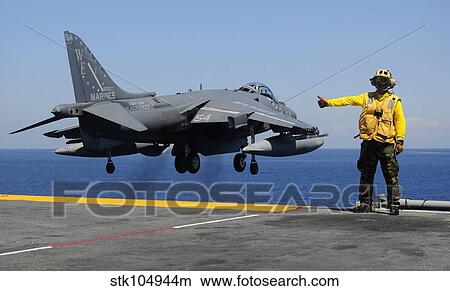 Picture - Airman gives the thumbs-up signal as an AV-8B Harrier takes off from the flight deck of USS Essex.. Fotosearch