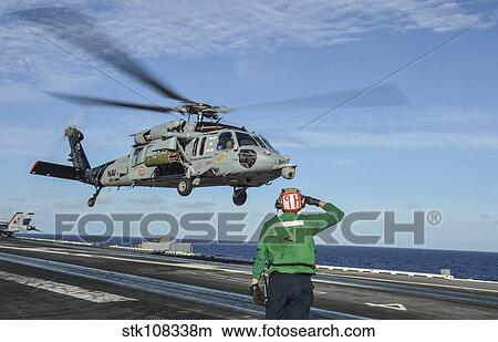 Airman salutes as a MH-60S Sea Hawk helicopter departs. View Large Photo Image Picture - Airman salutes as a MH-60S Sea Hawk helicopter departs.. Fotosearch