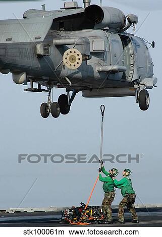 Airmen assist each other as they hook a sling to an SH-60B Seahawk. View Large Photo Image Picture - Airmen assist each other as they hook a sling to an SH-60B Seahawk.. Fotosearch