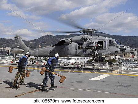 Airmen prepare to chock and chain an MH-60S Sea Hawk helicopter. View Large Photo Image Picture - Airmen prepare to chock and chain an MH-60S Sea Hawk helicopter.. Fotosearch
