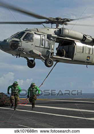 Airmen run to cover after attaching cargo legs to an MH-60S Sea Hawk. View Large Photo Image Picture - Airmen run to cover after attaching cargo legs to an MH-60S Sea Hawk.. Fotosearch