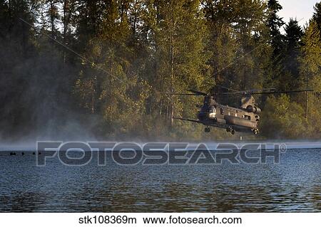 Airmen wait in a lake for an MH-47 Chinook helicopter to extract them. View Large Photo Image Picture - Airmen wait in a lake for an MH-47 Chinook helicopter to extract them.. Fotosearch