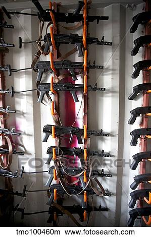 AKM assault rifles lined up on the wall in the armory. View Large Photo Image Picture - AKM assault rifles lined up on the wall in the armory.. Fotosearch
