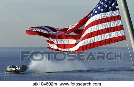American flag blowing in the wind with a hovercraft in the background. View Large Photo Image Picture - American flag blowing in the wind with a hovercraft in the background.. Fotosearch