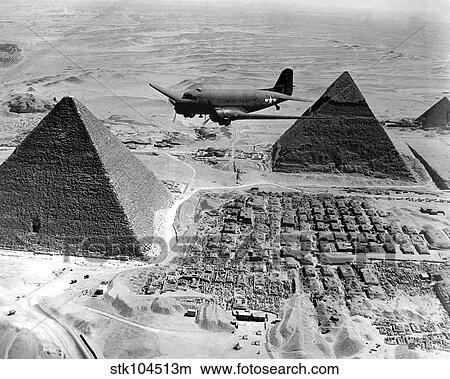 Picture - An Air Transport Command plane flies over the pyramids in Egypt.. Fotosearch