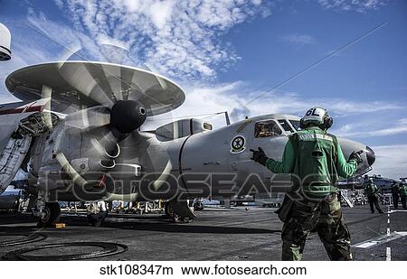 An aircraft director directs an E-2C Hawkeye aboard USS George Washington. View Large Photo Image Picture - An aircraft director directs an E-2C Hawkeye aboard USS George Washington.. Fotosearch