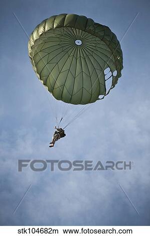 An Airman descends through the sky with parachute deployed. View Large Photo Image Picture - An Airman descends through the sky with parachute deployed.. Fotosearch