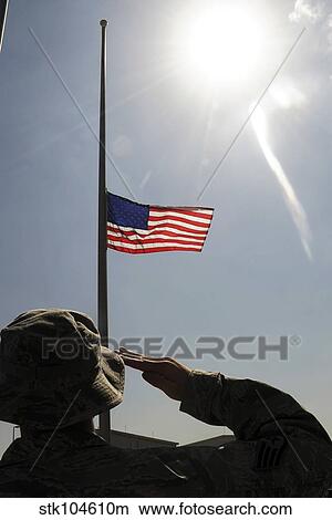 An Airman salutes the American flag that is flying at half-mast. View Large Photo Image Picture - An Airman salutes the American flag that is flying at half-mast.. Fotosearch