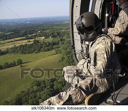 An Army crew chief looks out the door of a UH-60 Black Hawk helicopter. View Large Photo Image Picture - An Army crew chief looks out the door of a UH-60 Black Hawk helicopter.. Fotosearch