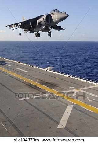 An AV-8B Harrier jet prepares to land on the flight deck of USS Essex. View Large Photo Image Picture - An AV-8B Harrier jet prepares to land on the flight deck of USS Essex.. Fotosearch