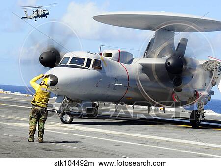 An Aviation Boatswain's Mate directs a French E-2C Hawkeye abord USS Theodore Roosevelt. View Large Photo Image Picture - An Aviation Boatswain's Mate directs a French E-2C Hawkeye abord USS Theodore Roosevelt.. Fotosearch