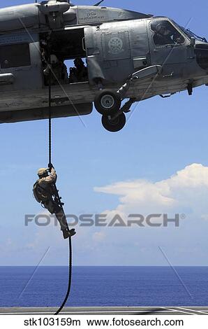 An explosive ordnance disposal technician fast ropes onto the flight deck of the USS Ronald Reagan. View Large Photo Image Picture - An explosive ordnance disposal technician fast ropes onto the flight deck of the USS Ronald Reagan.. Fotosearch