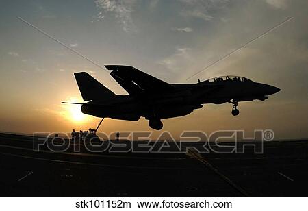 An F-14D Tomcat makes an arrested landing as the sun sets. View Large Photo Image Picture - An F-14D Tomcat makes an arrested landing as the sun sets.. Fotosearch