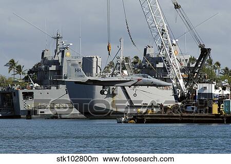 Picture - An F-15 Eagle gets a lift from a barge crane.. Fotosearch