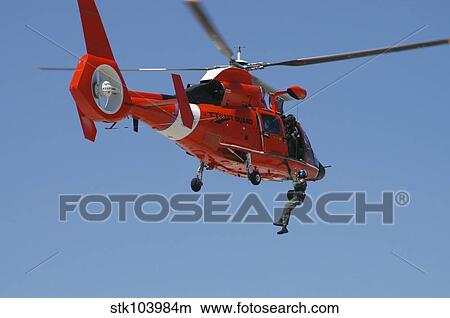 An HH-65C Dolphin demonstrates a helicopter rescue. View Large Photo Image Picture - An HH-65C Dolphin demonstrates a helicopter rescue.. Fotosearch