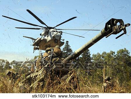 Picture - An MH-53E Sea Stallion helicopter preparing to lift an M777 105-mm lightweight Howitzer. . Fotosearch