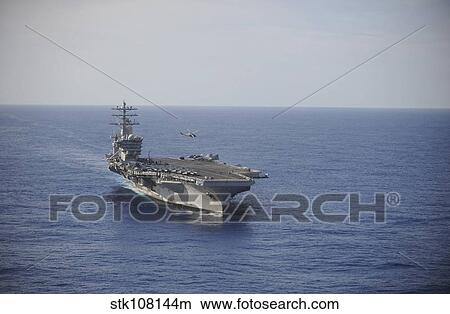 Picture - An MH-60R Sea Hawk helicopter performs maneuvers above USS Nimitz.. Fotosearch