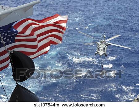 An MH-60S Sea Hawk carries supplies during a replenishment at sea. View Large Photo Image Picture - An MH-60S Sea Hawk carries supplies during a replenishment at sea.. Fotosearch