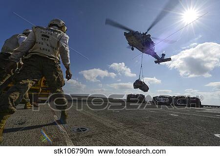 An MH-60S Sea Hawk helicopter lowers pallets of supplies onto USS Bonhomme Richard. View Large Photo Image Picture - An MH-60S Sea Hawk helicopter lowers pallets of supplies onto USS Bonhomme Richard.. Fotosearch