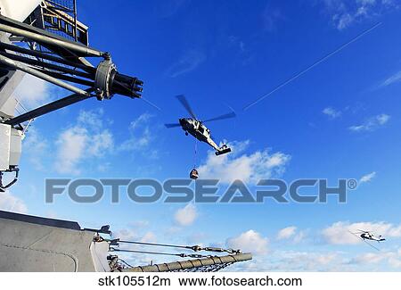 An MH-60S Sea Hawk helicopter transports cargo at sea. View Large Photo Image Picture - An MH-60S Sea Hawk helicopter transports cargo at sea.. Fotosearch