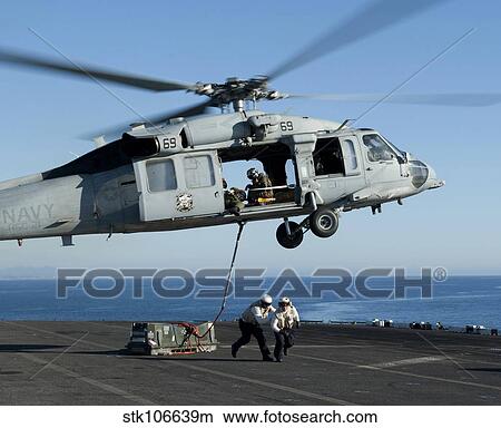 An MH-60S Sea Hawk helicopter prepares to lift crates from USS Makin Island. View Large Photo Image Picture - An MH-60S Sea Hawk helicopter prepares to lift crates from USS Makin Island.. Fotosearch