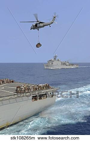 An MH-60S Sea Hawk helicopter transfers supplies during a replenishment at sea. View Large Photo Image Picture - An MH-60S Sea Hawk helicopter transfers supplies during a replenishment at sea.. Fotosearch