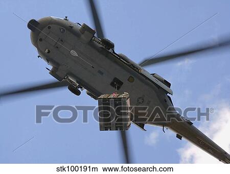 Picture - An MH-60S Seahawk helicopter airlifts a pallet of ammunition.. Fotosearch