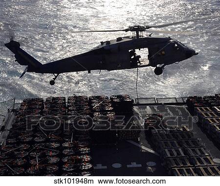An MH-60S Seahawk helicopter conducts a vertical replenishment. View Large Photo Image Picture - An MH-60S Seahawk helicopter conducts a vertical replenishment.. Fotosearch