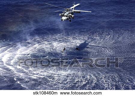 An MH-60S Seahawk lowers a rescue swimmer into the water. View Large Photo Image Picture - An MH-60S Seahawk lowers a rescue swimmer into the water.. Fotosearch