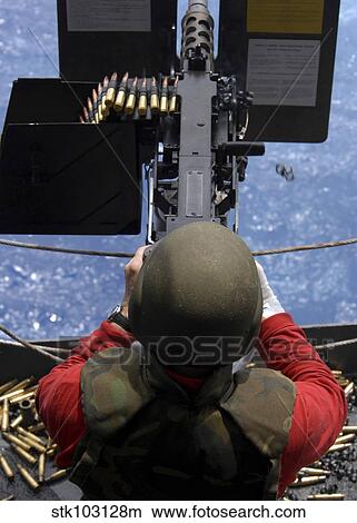 An Ordinance Handling Officer shooting a. 50 caliber machine gun aboard the USS George Washington. View Large Photo Image Picture - An Ordinance Handling Officer shooting a. 50 caliber machine gun aboard the USS George Washington.. Fotosearch