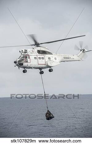 An SA-330 Puma transport helicopter moves cargo during a vertical replenishment. View Large Photo Image Picture - An SA-330 Puma transport helicopter moves cargo during a vertical replenishment.. Fotosearch