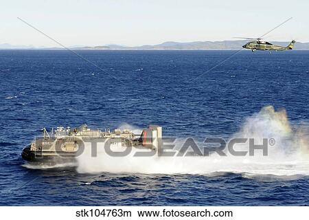 An SH-60F Seahawk helicopter follows a Landing Craft Air Cushiion in the Coral Sea. View Large Photo Image Picture - An SH-60F Seahawk helicopter follows a Landing Craft Air Cushiion in the Coral Sea.. Fotosearch