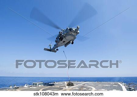 An SH-60R Seahawk delivers supplies during a vertical replenishment. View Large Photo Image Picture - An SH-60R Seahawk delivers supplies during a vertical replenishment.. Fotosearch