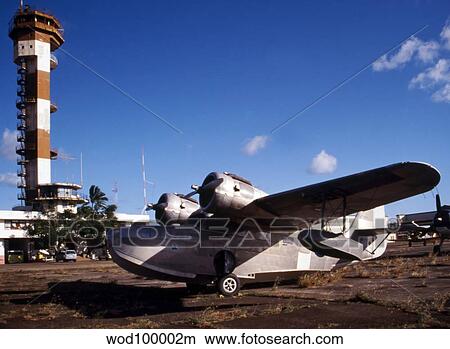 Picture - Antique Navy Seaplane parked in front of the World War II Control Tower on Ford Island, Pearl Harbor, Hawaii.. Fotosearch
